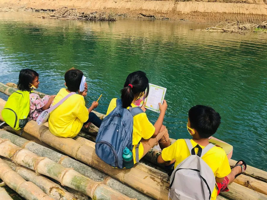 Kids reading on a bamboo raft